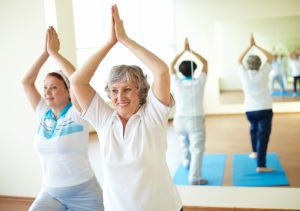 Portrait of two aged females doing yoga exercise in sport gym